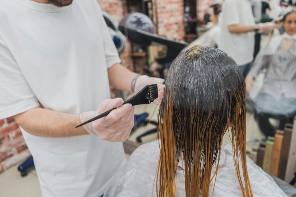 Hair coloring process in a salon, showcasing stylist applying color to client's hair.